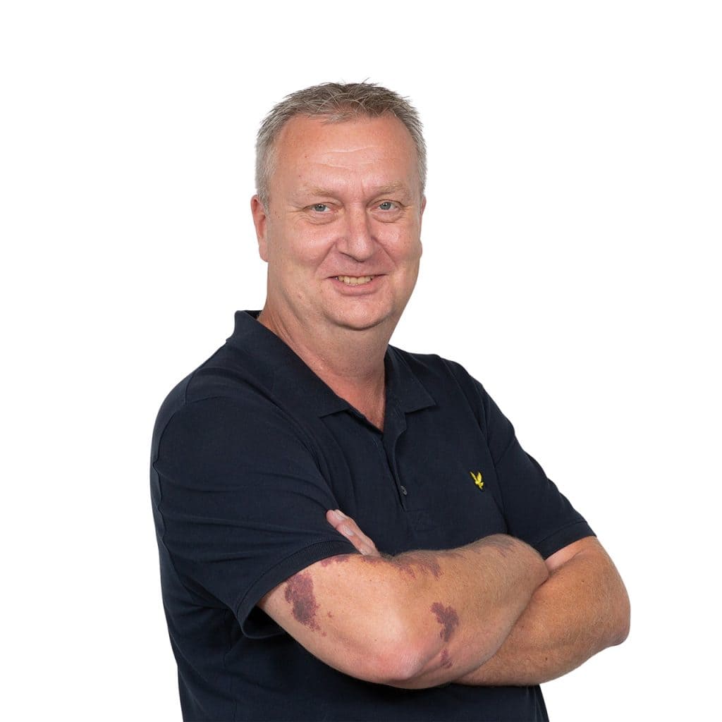 Zorgprofessional met huidproblemen in een zwart polo, witte achtergrond, focus op gezicht en armen, professioneel portret voor gezondheidszorg en huidbehandeling.